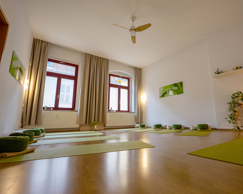 Großer Raum mit Yogamatten und Fenstern zum Hof